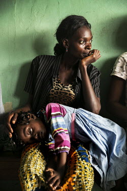 A woman waits, with her sick daughter, for a consultation with medical staff at a health centre.