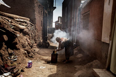 A woman burns household waste in an alley at the back of her home. The town is known for its unusual red-coloured brick architecture.
