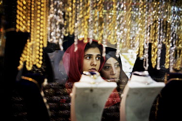 A woman and a girl look at the gold and silver items displayed in the window of a jewellery shop in the bazaar.