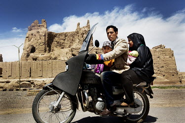 A family driving on a motorbike pass the Narenj Ghaleh, the Castle of Na'in.