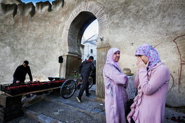 Two women, wearing pink clothes, stand at the entrance to the souq.