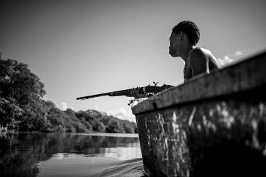 Jeff heads out on his boat to hunt garca birds with his gun in the mangroves around his house in the small fishing community of Pocas on the Bahian coast.