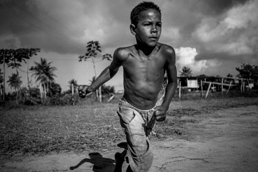 A young boy plays football in a field on the road between Conde and Acaraju in Northeast Brazil.