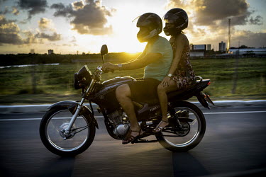 A couple rides on a motorcycle at sunset in Acaraju.