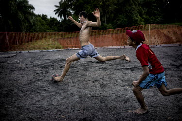 Local boys play football on a gravel construction zone near Arena Pernambuco in Sao Lourenco da Mata, outside of Recife, Brazil.   The construction zone was meant to be a road to the new stadium but i...