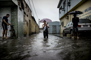 Locals wade through the water of the flooded streets of Recife after a day of torrential rainfall.