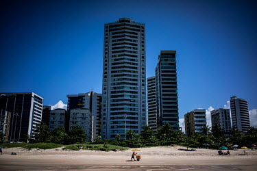A man with a trolley selling refreshments walks along a beach in Recife.