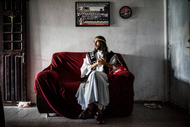 Pedro Luna, also known as Jesus Tricolor, puts on his 'crown of thorns' in front of a flag of the Santa Cruz football team. He is known for dressing up like Jesus Christ wearing the colours of the foo...