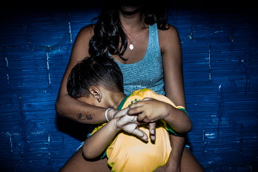 A boy hides from the camera in his mother's arms in Fortaleza.
