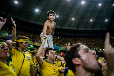 A boy stands on the shoulders of a man during the Brazil vs Colombia quarter final match during the 2014 Football World Cup. Brazil won the game 2:1.
