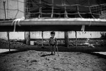 Luis, 3, holding a stick, plays beneath a trampoline along the road from Fortaleza to Jericoacoara in Northern Brazil.