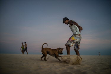 A man plays football with his dog on a beach in Jericoacoara.