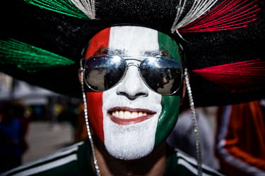 A Mexico fan with his face painted in the national colours and wearing a sombrero and sunglasses at the Mexico vs Netherlands game in Fortaleza. The Netherlands won the game 2:1.