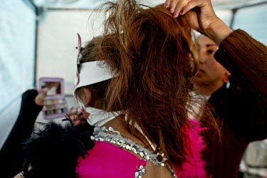 A friend styles her hair while a Cholita Luchadores (Cholitas are wrestlers of native Aymara descent) applies makeup prior to entering the ring for her bout.