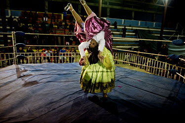 A Cholita (wrestler of native Aymara descent) attempts to pin down her opponent with an acrobatic manoeuvre during a bout at the 12 October Stadium in the El Alto district.