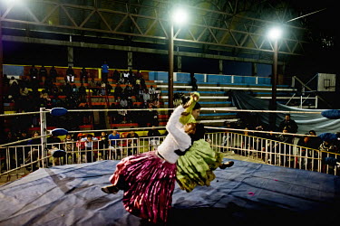A Cholita (wrestler of native Aymara descent) attempts to put her opponent on the canvas with an acrobatic manoeuvre during a bout at the 12 October Stadium in the El Alto district.