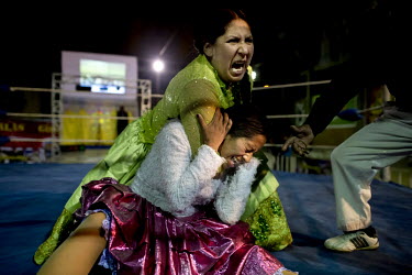 Marta La Altena (a Cholita or wrestler of native Aymara descent) puts Denita La Intocable into a rear naked choke during their fight at a repurposed warehouse in El Alto. Denita's plight is not helped...