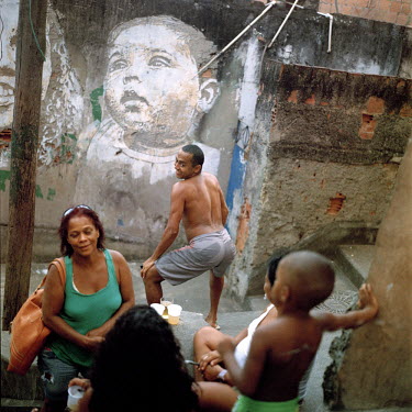 A man plays about with a woman and some children near a graffiti of a baby. At 115 years old, Providencia is Rio de Janeiro's oldest favela, originally formed when veterans of the bloody Canudos war i...