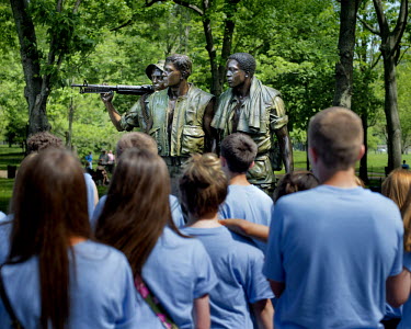 A class of schoolchildren in front of The Three Soldiers, a monument which is part of the Vietnam Veteran's Memorial at the National Mall.
