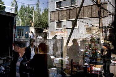 People reflected in a window as they congregate at market stalls in a residential complex housing workers, and their dependants, of the Datong Coal Mine Group's (Tong Mei) Yong Ding Zhuang coal mine.