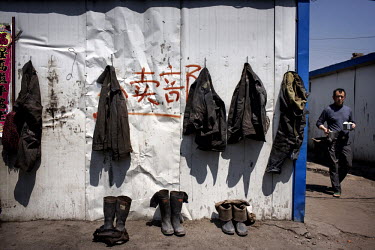 A coal miner carries his lunch past fellow worker's clothes hanging on their dormitory wall at the Datong Coal Mine Group's (Tong Mei) Tong Xiu coal mine.