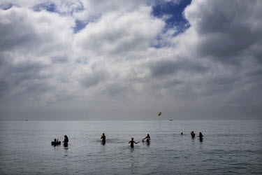 Tourists swimming in the sea. The long broad beach, stretching from Fuengirola, is crowded with tourists during the day throughout the summer months but in the mornings and late eveings, the sun hungr...