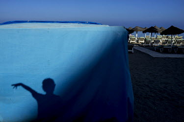 A visitor's shadow falls on a shack. The long broad beach, stretching from Fuengirola, is crowded with tourists during the day throughout the summer months but in the mornings and late eveings, the su...