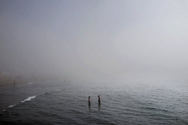 Children in the sea enveloped by wispy morning fog on the beach at Torreblanca. The long broad beach, stretching from Fuengirola, is crowded with tourists during the day throughout the summer months b...