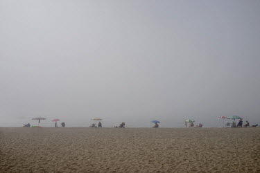 People on the beach at Torreblanca are enveloped by a morning fog. The long broad beach, stretching from Fuengirola, is crowded with tourists during the day throughout the summer months but in the mor...