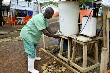 A MSF (Doctors Without Borders) doctor washes his hands with chlorine after finishing his work at the field hospital established to fight Ebola virus in Gueckedou. An Ebola virus epidemic of unprecede...