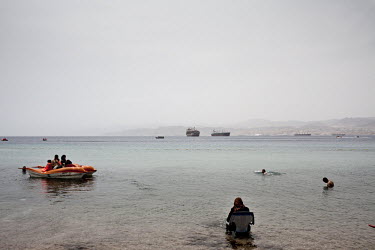 A woman sits in a chair in the shallows of the Red Sea off the coast of Aqaba.