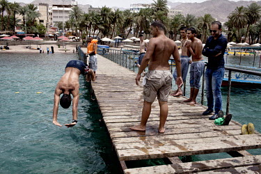 A man dives into the Red Sea from a jetty that extends from the shore.