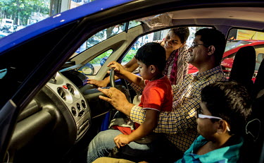 A young, middle-class family, try out the new Nano Twist car in a Tata Motors showroom.