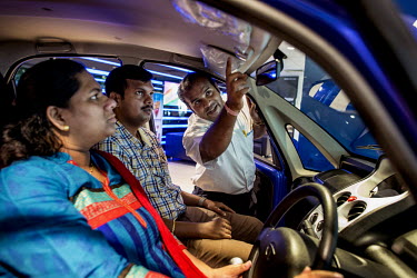 A Tata Motors salesperson explains the features of the new Nano Twist car to a couple at a Tata Motors showroom.