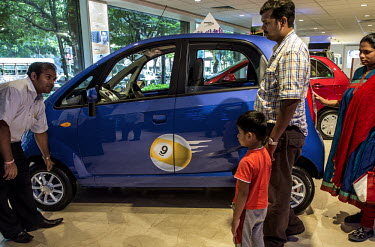 A Tata Motors salesperson explains the features of the new Nano Twist car to a young family at a Tata Motors showroom.