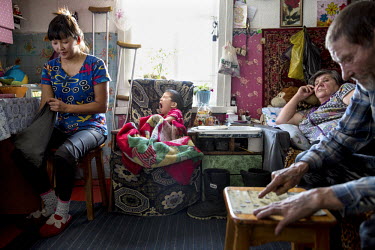 Vladimir Petrenko (right), who has liver problems, sits at home with with his invalid wife, Lubov (reclining on bed), their daughter-in-law, Elena, and grandson, Valery, who suffers from hemophilia. T...