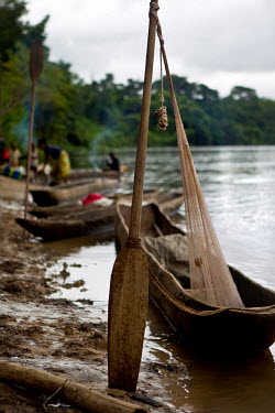 A dugout canoe is tethered by an oar and a fishing net to the banks of the Aruwimi River.
