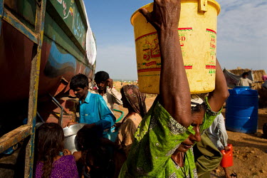 A woman collects a container of water at a camp for people displaced by floods that hit the country in July 2010.
