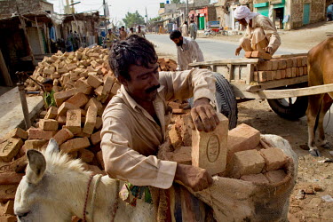 A man loads a panier with bricks at a factory which is operating at full capacity so that people whose houses have been destroyed by the floods that hit the country in July 2010 can start to rebuild.