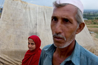 A man and his daughter standing outside a tent in a refugee camp after the Kabul River flooded.