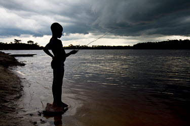 A boy fishing in the Lomami River for small fish uses a stick as a rod.