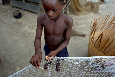A boy repairs a fishing net.