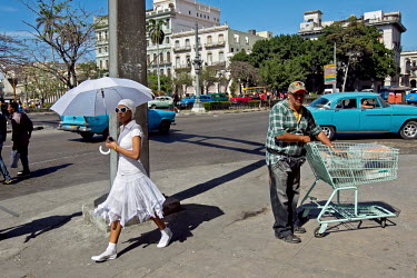 A Santeria practitioner walks through the city centre, past a man pushing a supermarket trolly along the pavement. After their initiation Santeros must wear white year, they may not drink alcohol and...