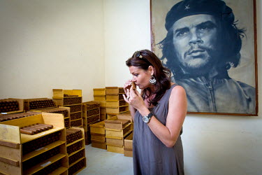 Well-known Belgian, sexologist and former Miss Belgium, Goedele Liekens smelling a Cohiba cigar during her visit to the cigar factory in Havana. In the background is a poster of Che Guevara.