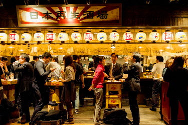 Businessmen and women have drinks and dinner after work at the Nippon Saisei Sakaba-Japan Regeneration Bar at the Shin-Marunouchi Building in front of Tokyo Station.