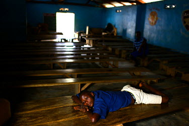 A boy relaxes inside a local theater where locals used to watch football. Now the theater is close as the government has banned public gatherings in private places.The government of Sierra Leone decla...