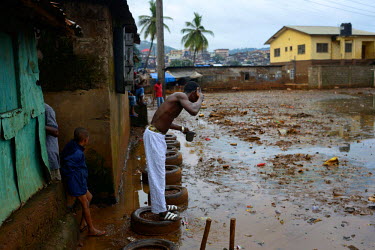 A man washes his face at the entrance to his house in the Kroo Bay Slum area. People have been instructed to listen to police and volunteer workers who will pass through the slum, telling people about...