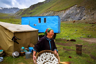 A woman carries a basket of Kumus balls, made from fermented horse milk. Her family practice transhumance with their animals and will spend the rest of the summer in a temporary camp in the mountains.