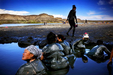A group of women wallow in a pool of black mud at the Kara Kul salt lake. The mud contains minerals that are considered to be good for treating skin conditions