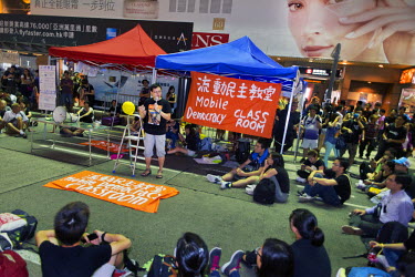 A man holding a microphone gives a speech at a 'Mobile Democracy Class Room' set up on a street in Hong Kong during pro-democracy demonstrations.   The 'Occupy Central ' (or 'Occupy Central with Love...